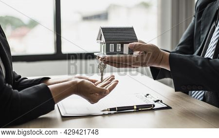 The Salesperson Handed The Small Gray Model Of The House And The House Keys To The Customer As A Sig