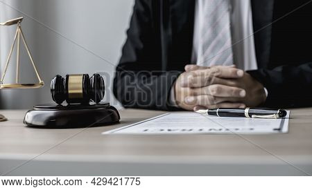 A Male Lawyer Sits In His Office, On A Table With A Small Hammer To Beat The Judge's Desk In Court.
