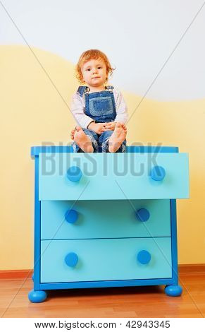 Barn sidder på kabinettet