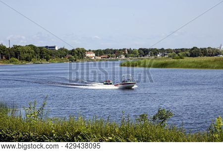 Latvia, Jurmala, August, 2021 - Motor Boat Rides Of People On Inflatable Sofa Down The Lielupe River