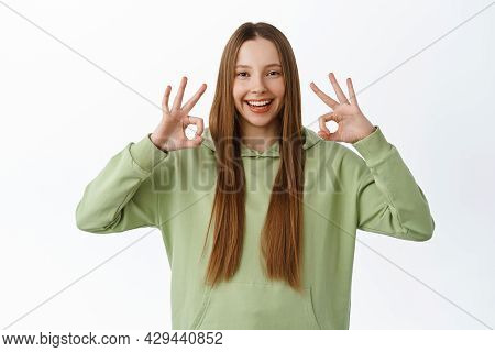 Very Good. Beautiful Female Student, Teenager Shows Okay Sign And Say Yes, Smiling Pleased, Approve 
