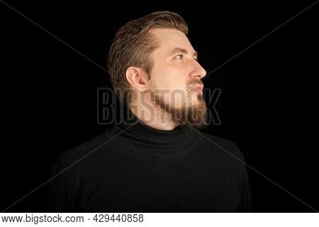 Cute Bearded Man, Half-face Portrait, Black Background. Young Guy In Black Polo Neck Sweater. Confid