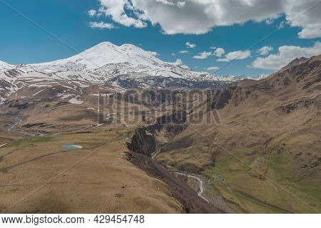 Mountains Above River Meadows Under A Blue Sky