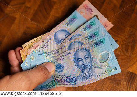 Male Hand Holds A Fan Of  Vietnames Dong Banknote, The Currency Of Vietnam.  Close Up Polymer Money 