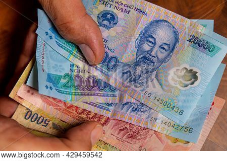 Male Hand Holds A Fan Of  Vietnames Dong Banknote, The Currency Of Vietnam.  Close Up Polymer Money 