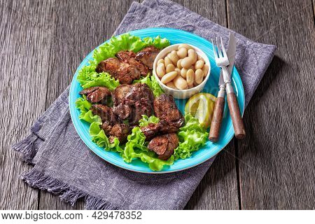 Chicken Liver Fry, Kaleji Fry, Served On Lettuce Leaves With Butter Beans And Lemon Wedges On A Blue