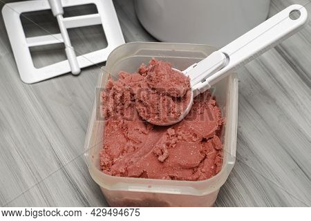 Homemade Cherry Ice Cream In A Plastic Container On The Table With An Ice Cream Spoon And An Ice Cre