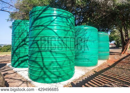 Four Large Green Colored Water Tanks About Six Thousand Liter Holding Liquid Capacity On Conceete Ba