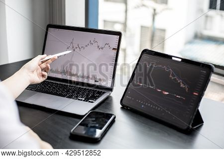 A Stock Investor Holding A Pen Pointing To A Laptop Screen Opens A Stock Chart Program To Read Stock