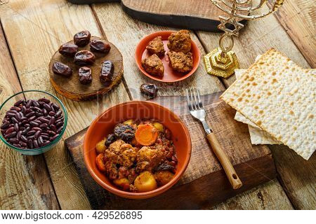 Jewish Dish Chelnt With Meat On A Stand Next To Matzo, Fork And Ingredients. Horizontal Photo