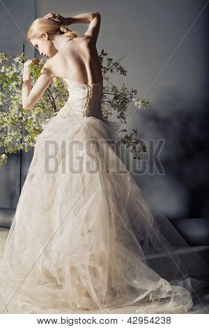 Bride in wedding dress behind bush with flowers