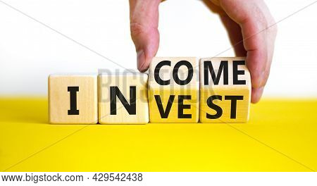 Invest Or Income Symbol. Businessman Turns Wooden Cubes And Changes The Word 'invest' To 'income'. B