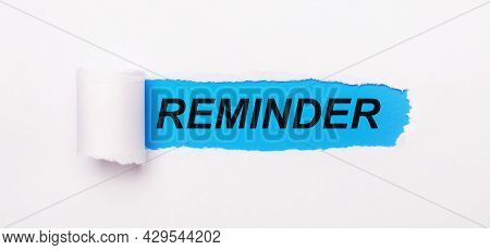 On A Bright Blue Background, White Paper With A Torn Stripe And The Text Reminder