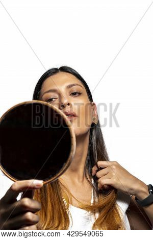 Young Latinx Woman Checking Her Hair In Mirror, Isolated On White Background.