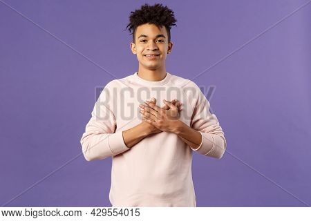 Portrait Of Romantic Handsome Hispanic Man With Dreads, Hold Hands Pressed To Heart And Smiling Plea