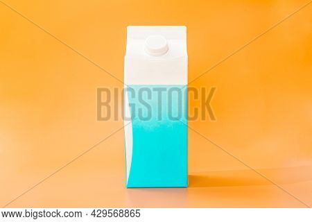 White And Blue Cardboard Box Of Milk On A Orange Background. Eco Food. 2 Litres Paper Bottle Of Milk