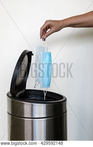 A Womans Hand Throwing Out Madical Face Masks In A Rubbish Bin
