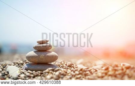 Zen Stones Are Background. A Pyramid Of Pebble Stones Against The Background Of The Sky, Sea And Bea