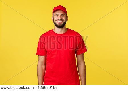 Express Mail Delivery, Package Transfer And Logistics Concept. Cheerful Young Bearded Courier In Red