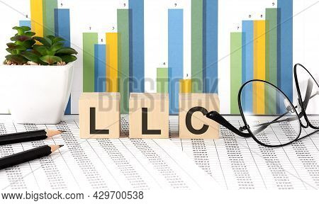 Llc Word Written On Wood Block With Chart, Glasses And Pencils