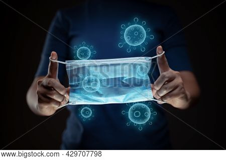 Close Up Shot Of Hands Holding Protective Face Mask With Virus Hologram Effect.