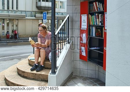 Zurich, Switzerland, July 10, 2017: Woman Reading A Novel By Honore De Balzac By A Street Book Excha