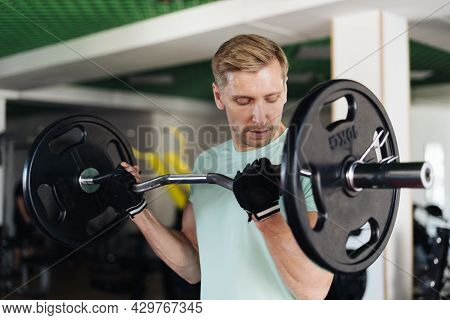 Athlete Man Lifting Barbells Working Out With Curl Bar In The Gym Doing Elevations. Caucasian Male T
