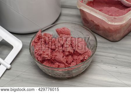 Homemade Cherry Ice Cream In A Glass Socket And A Plastic Container On The Table Next To An Ice Crea