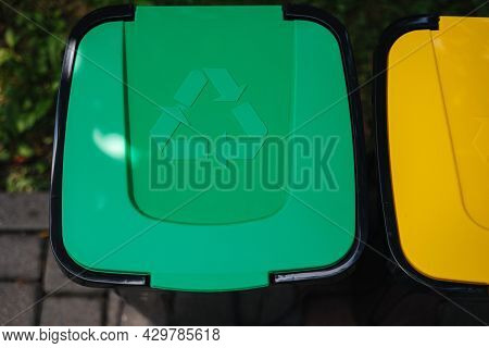 Outdoors In The Park Is Recycling Bins Different Colours. Tree Closed Plastic Bins. Green, Yeallow A