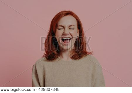 Overjoyed Red Haired Caucasian Woman Laughing Positively, With Closed Eyes, Expressing Positive Emot