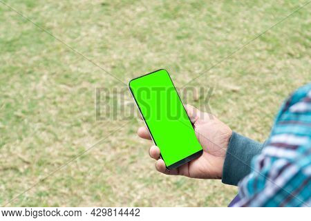 Hand Holding Phone With The Green Color In Front Of A Floor Background,smartphone In Hand With A Gre