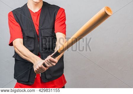 A Baseball Bat In The Hands Of A Young White Man In A Black Vest. Strong Hands Grip The Bat