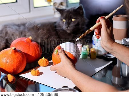 Do It Yourself. Dyi. Women's Hands Painting A Small Pumpkin In White. Making Decorations For Hallowe