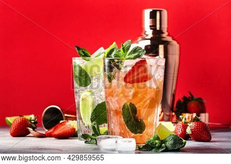 Cuople Of Mojito Cocktails Or Mocktails With Lime, Rum, Mint, Strawberry And Ice In Glass On Red Bac