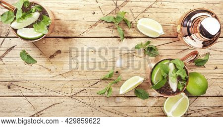Moscow Mule Cocktails In Copper Mug With Lime, Ice, Ginger Beer, Vodka And Mint. Wooden Background, 