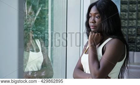 Upset Worried African-american Woman With Long Hair In Sleeveless Shirt And Crossed Arms Looks Out O