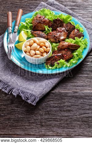 Chicken Liver Fry, Kaleji Fry, Served On Lettuce Leaves With Butter Beans And Lemon Wedges On A Blue