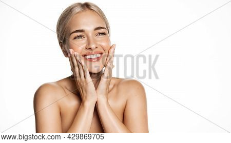 Spa And Cosmetology. Young Blond Woman Smiling Happy, Looking Up, Holding Hands On Face, Apply Moist