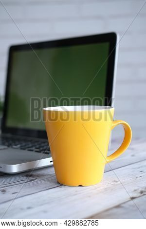 Yellow Color Coffee Mug And Laptop A On Table