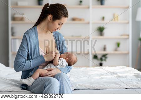 Lactation Concept. Beautiful Smiling Woman Feeding Newborn Baby With Breast At Home