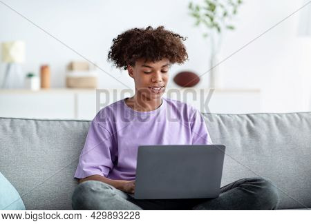 Home Schooling. Black Teenage Guy Having Online Class, Using Laptop, Talking To Fellow Students Or T