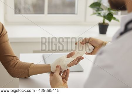 Doctor Or Nurse At Medical Office Wrapping Patients Sprained Wrist With Bandage