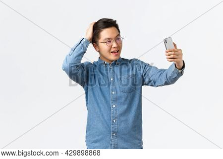 Cheeky Confident Asian Man In Glasses And Braces Feeling Sassy, Taking Selfie, Brushing Hair With Ha