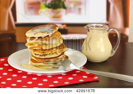 หวาน pancakes บนแผ่นกับนมข้นบนโต๊ะในห้อง