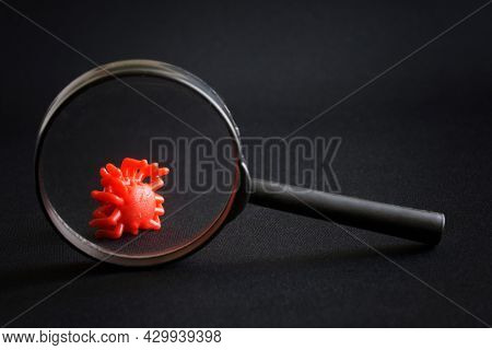 Toy Virus Under A Magnifying Glass Against A Black Background. The Concept Of Studying New Viruses, 