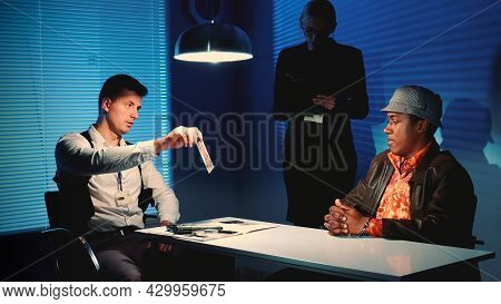 Medium Shot Of Detective Showing Picture Of Suspected Robbers Accomplice During Interview In Police 