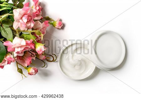 White Jar And White Cap With Body Cream On White Background With Artificial Rose Flowers. White Jar 