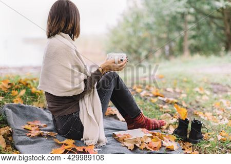 Pretty Woman Turned Away From The Camera And Looking On Water. Girl In Brown Sweater, Black Jeans An