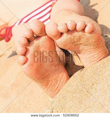 Child's Foot Is Close To The Sandy Beach