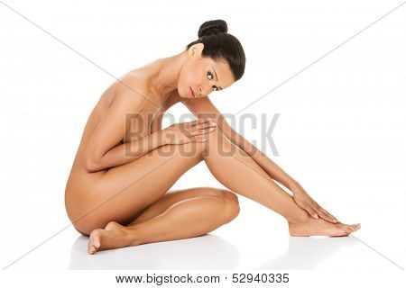 Beautiful and naked woman sitting. Side view. Legs half-straight. Isolated on white. 